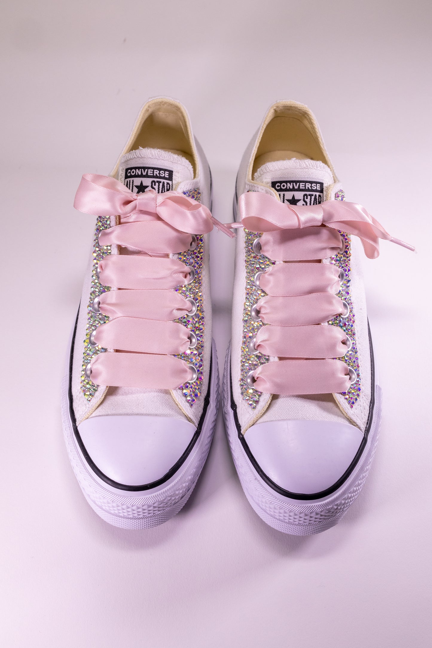 Converse shoes with pink laces and embellishments on a light background