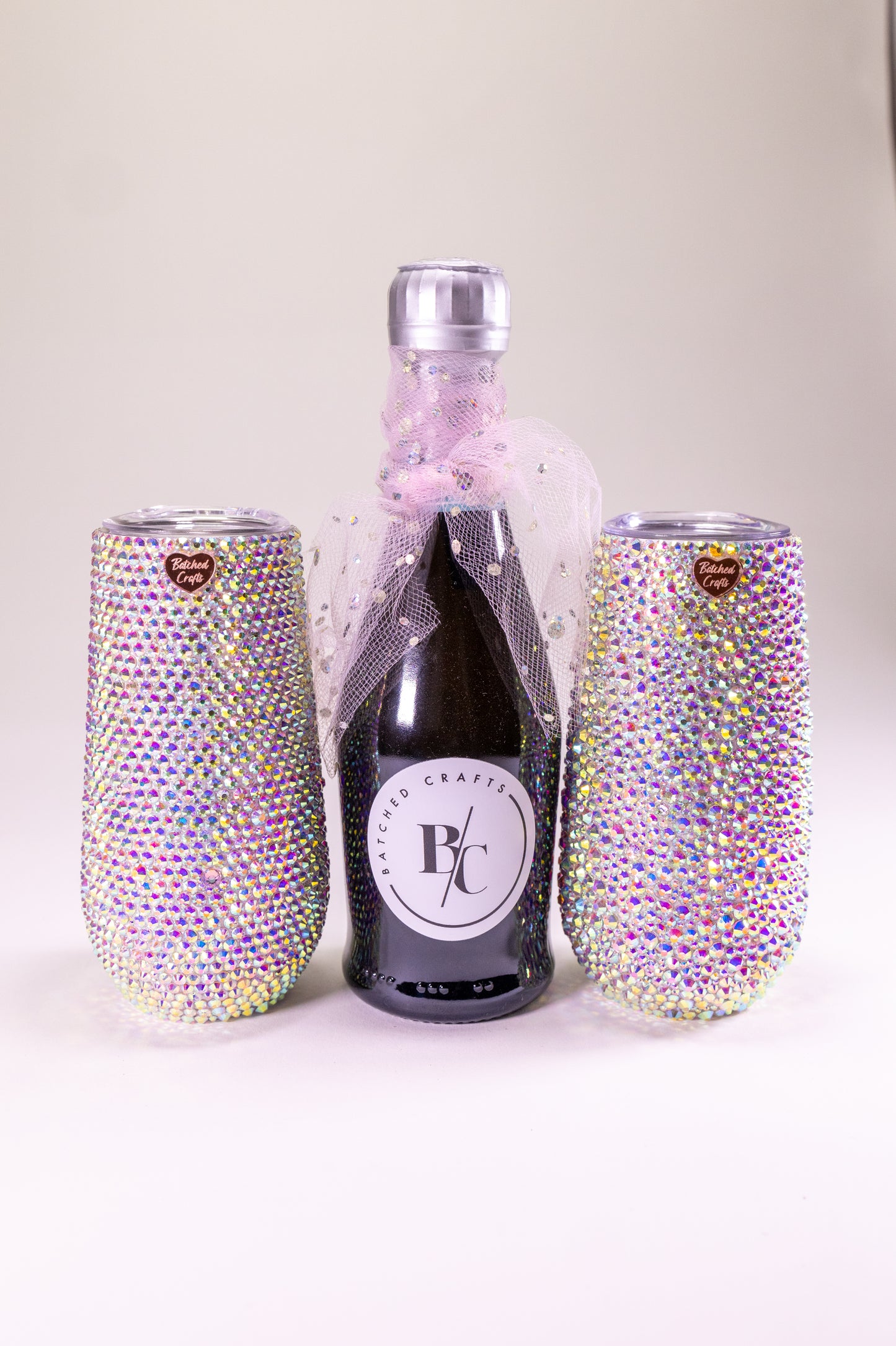Bottle of sparkling wine with two blinged-out tumblers on a white background