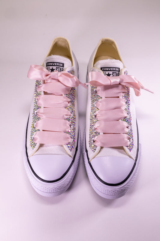 Converse shoes with pink laces and embellishments on a light background