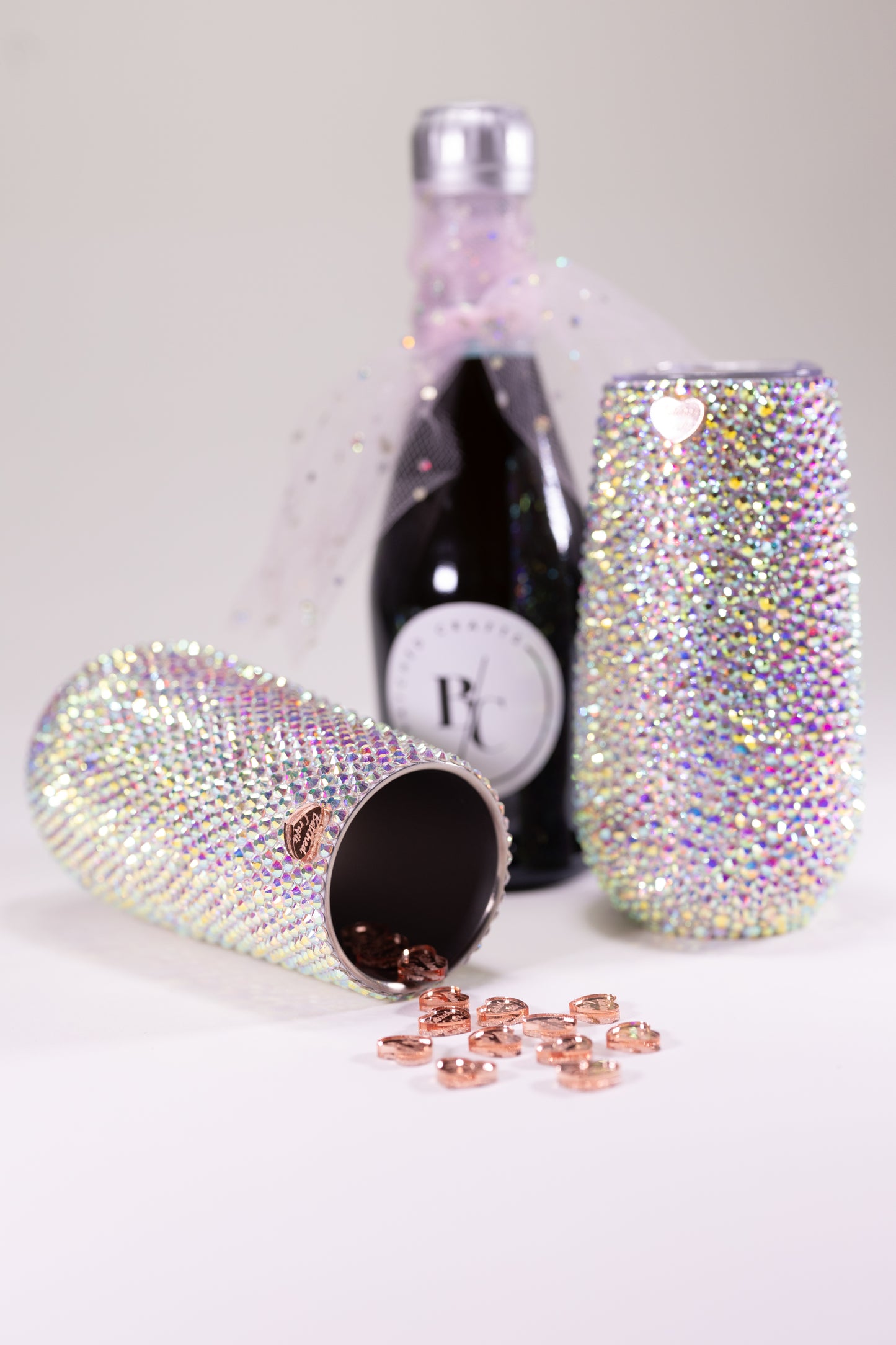 Two sparkling tumblers with a bottle of sparkling wine on a light background