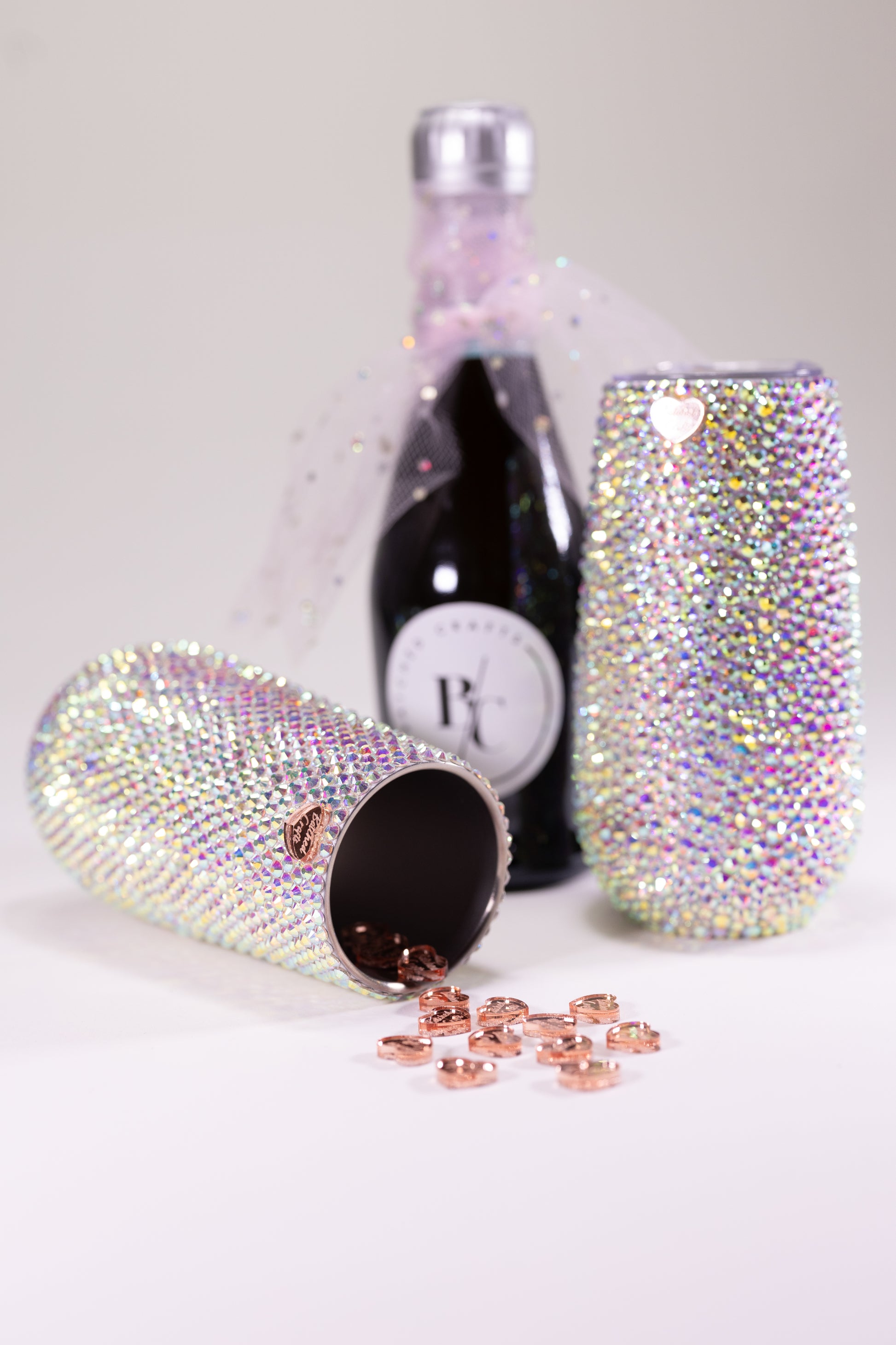 Two sparkling tumblers with a bottle of sparkling wine on a light background