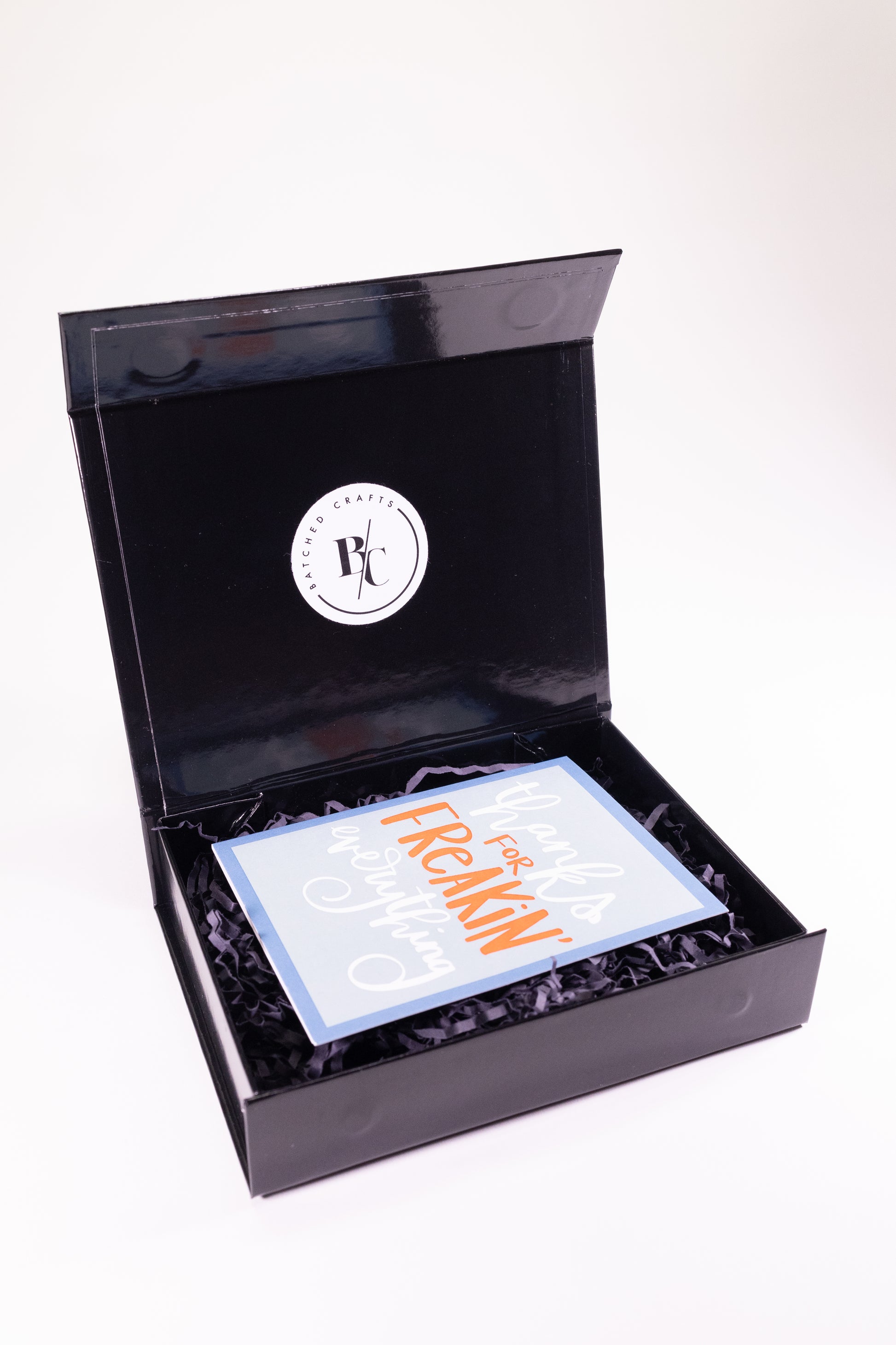 Black gift box with a thank you card inside on a white background