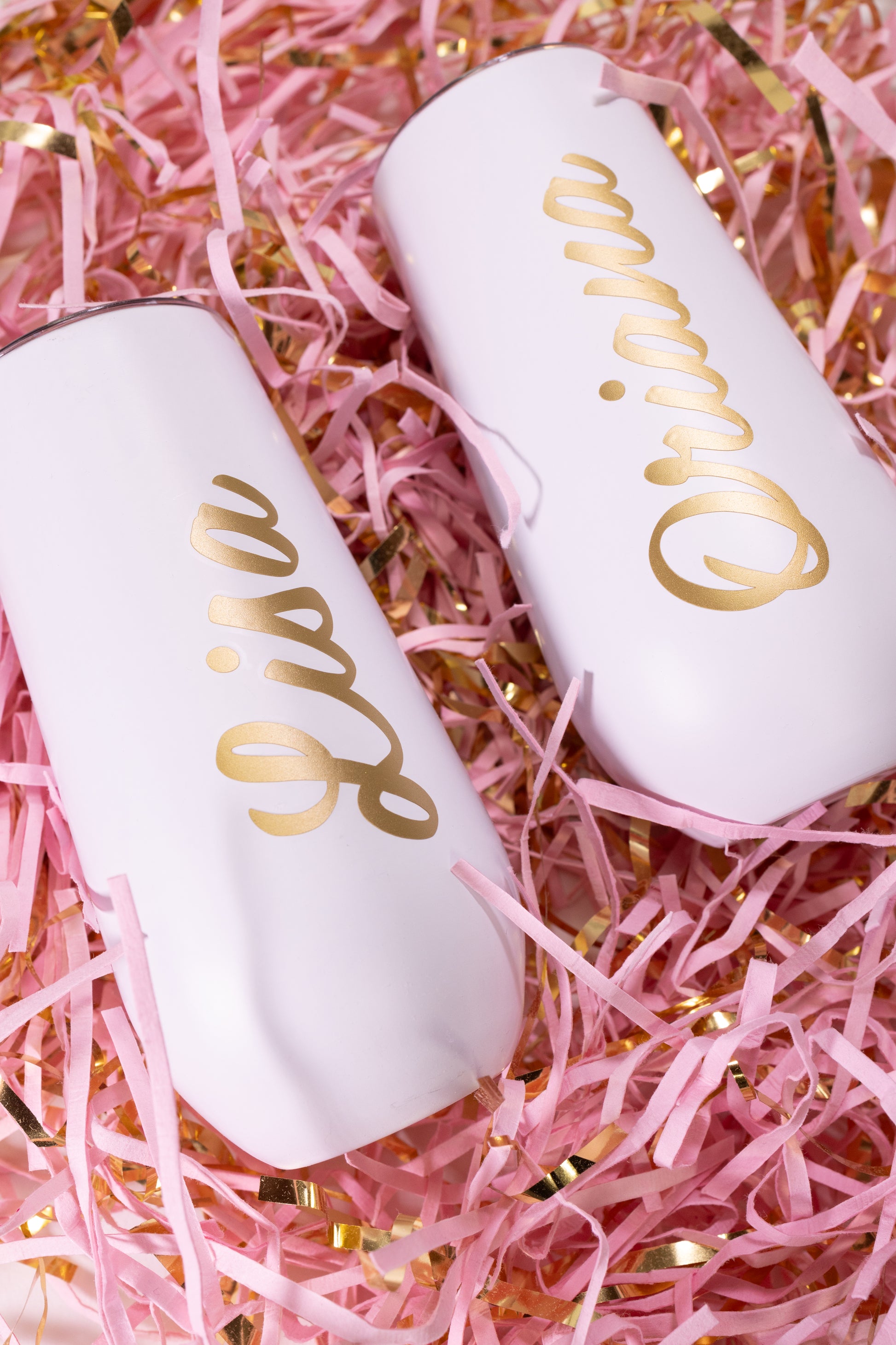 Two white stemless tumblers with gold names.
